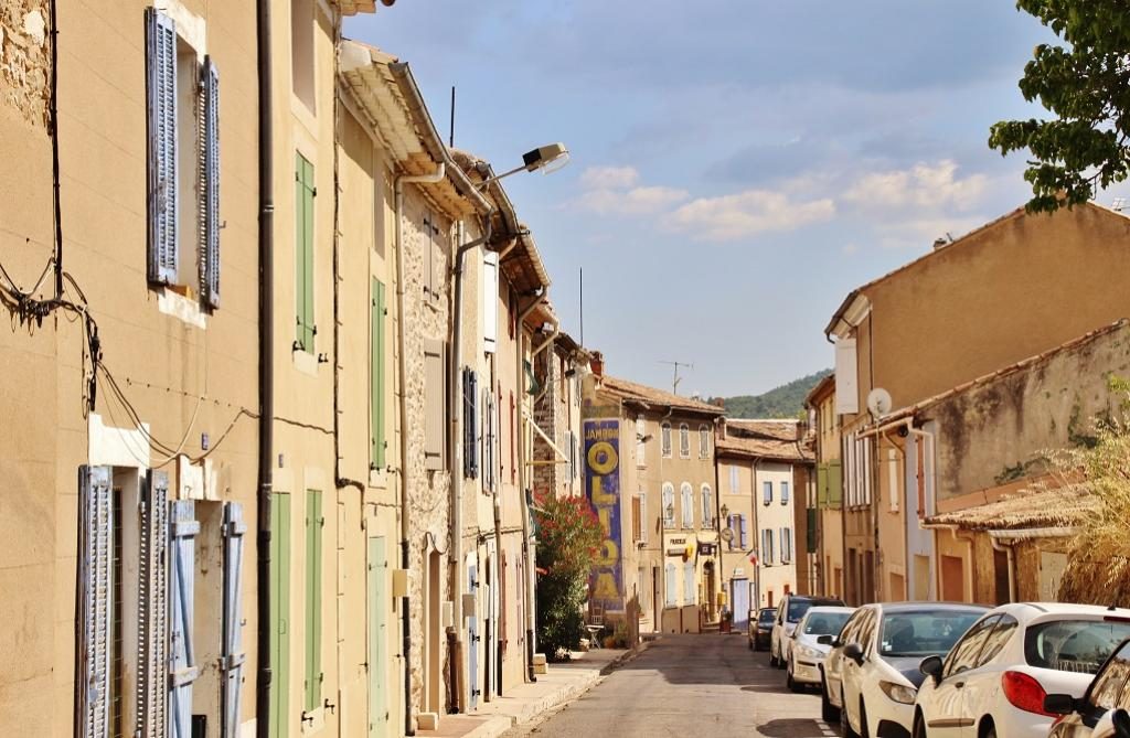 La rue du village, ses façades colorées et ses volets, sous un ciel bleu
